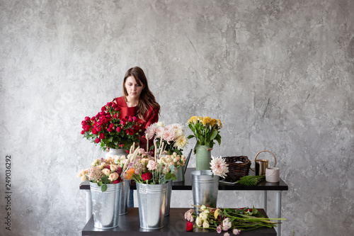 Florist workplace. Woman arranging a bouquet with roses, chrysanthemum, carnation and other flowers. A teacher of floristry in master classes or courses