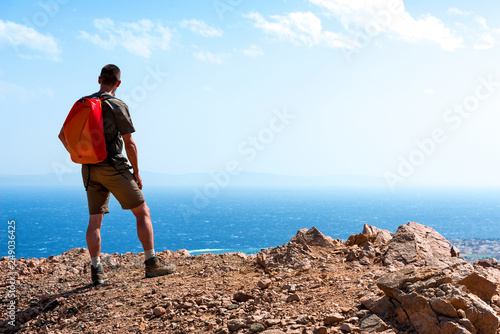 man stands on top of a mountain over the coast of the red sea. travel concept