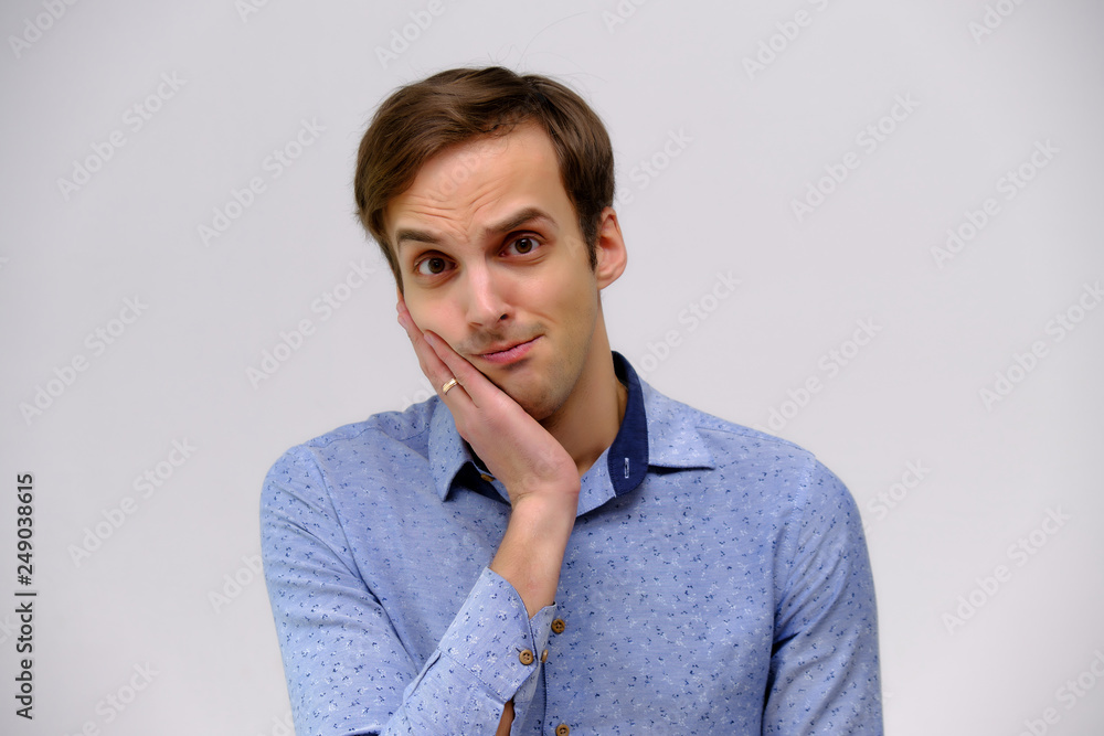 Concept studio portrait of a handsome young man isolated on a white background with different emotions in a blue shirt Concept studio portrait of a handsome young man isolated on a white background with different emotions in a blue shirt