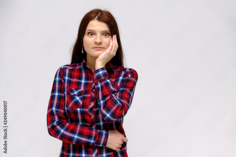 Concept studio portrait of a beautiful young beautiful brunette girl on a white background with different emotions in a multi-colored shirt. Concept studio portrait of a beautiful young beautiful brunette girl on a white background with different emotions in a multi-colored shirt.