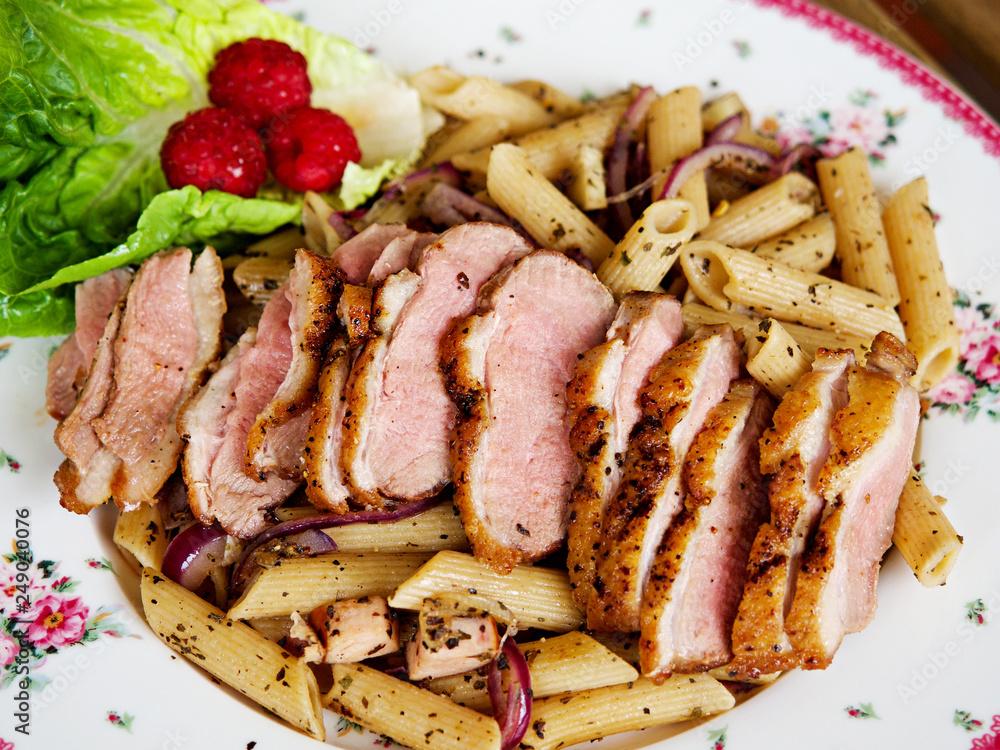 Penne pasta with grilled roast duck breasts slices and olive oil, basils and black peppers. Fusion food.