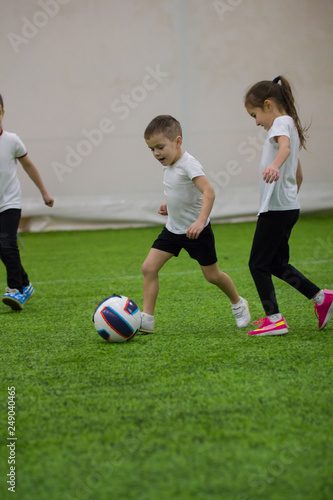 Little children kicking the ball on the field playing football
