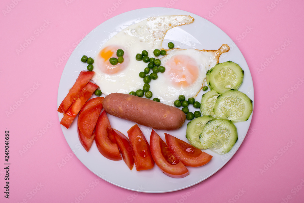 Homemade fried eggs with sausages on a white plate on a pink background. Classic breakfast. View from above. Homemade fried eggs with sausages on a white plate on a pink background. Classic breakfast. View from above.