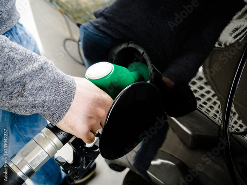 Refueling the car, a man's hand keep a nozzle to pour fuel