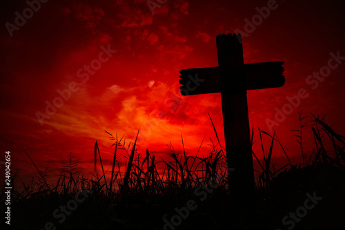 Scary background cemetery cross with dark silhouette in twilight sky, concept of horror and Halloween