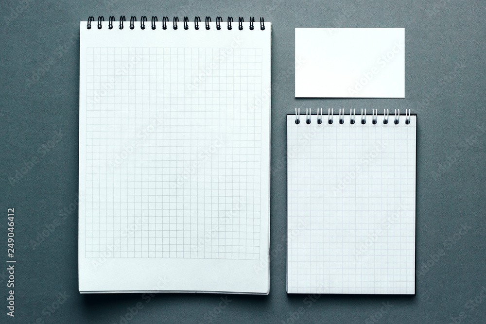 Top view of two open spiral blank notebook and blank bussines card. Mock up on gray background.