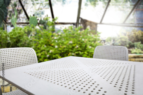 White table of free space with two chairs and spring garden background. 