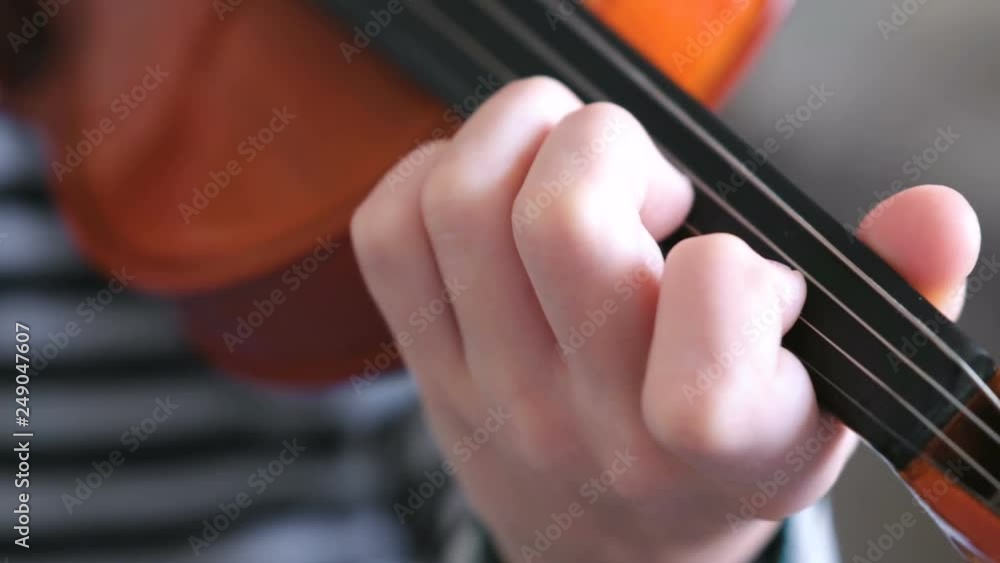 Violin in boy's hands. Boy is learning to play violin. Correct setting of the fingers of the left hand on the strings of the violin. Violin in boy's hands. Boy is learning to play violin. Correct setting of the fingers of the left hand on the strings of the violin.