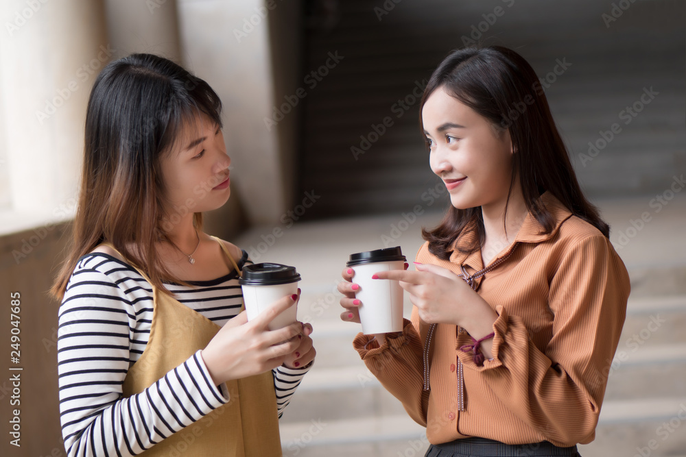 asian woman friend talking about gossip; portrait of two friendly woman drinking coffee while gossiping, concept of friendship, social trend, casual news update; young adult asian woman model asian woman friend talking about gossip; portrait of two friendly woman drinking coffee while gossiping, concept of friendship, social trend, casual news update; young adult asian woman model