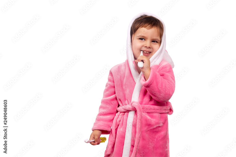 Emotional сlose up cute little girl in pink bathrobe cleaning teeth with electrical toothbrush Isolated on white background Emotional сlose up cute little girl in pink bathrobe cleaning teeth with electrical toothbrush Isolated on white background