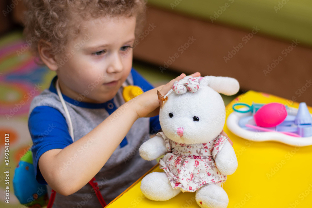 Little boy plays doctor, treats a teddy bunny Little boy plays doctor, treats a teddy bunny