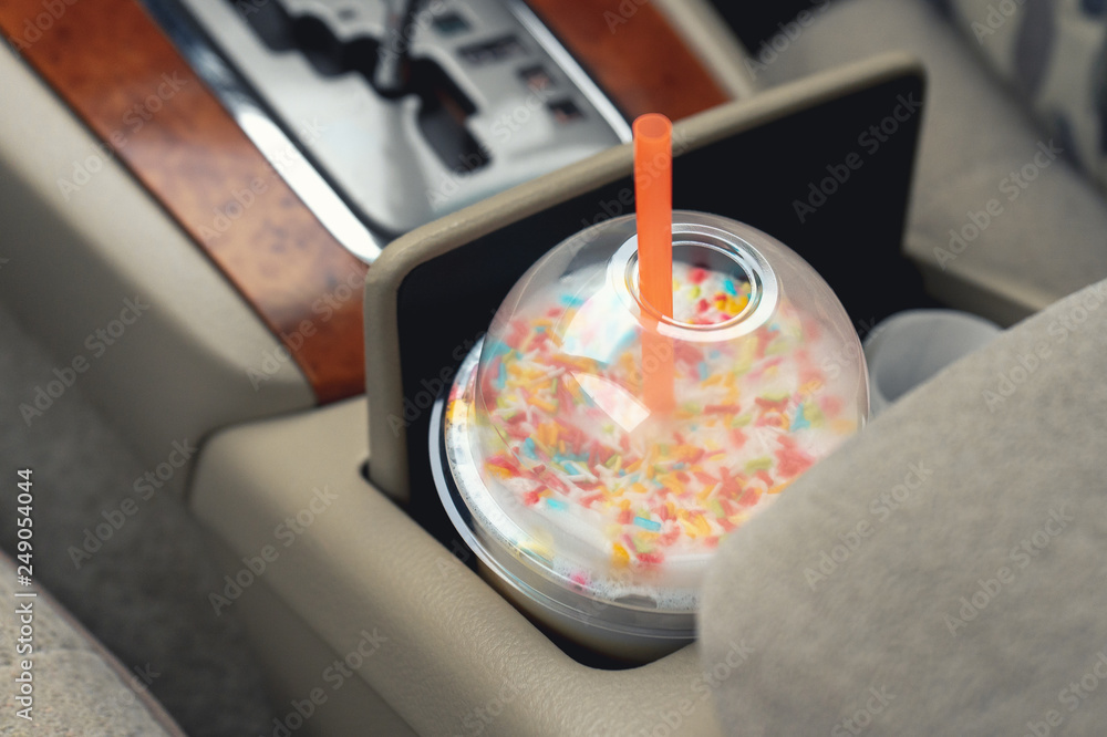 Cup of cappuccino with tube in Cup holder in car Cup of cappuccino with tube in Cup holder in car