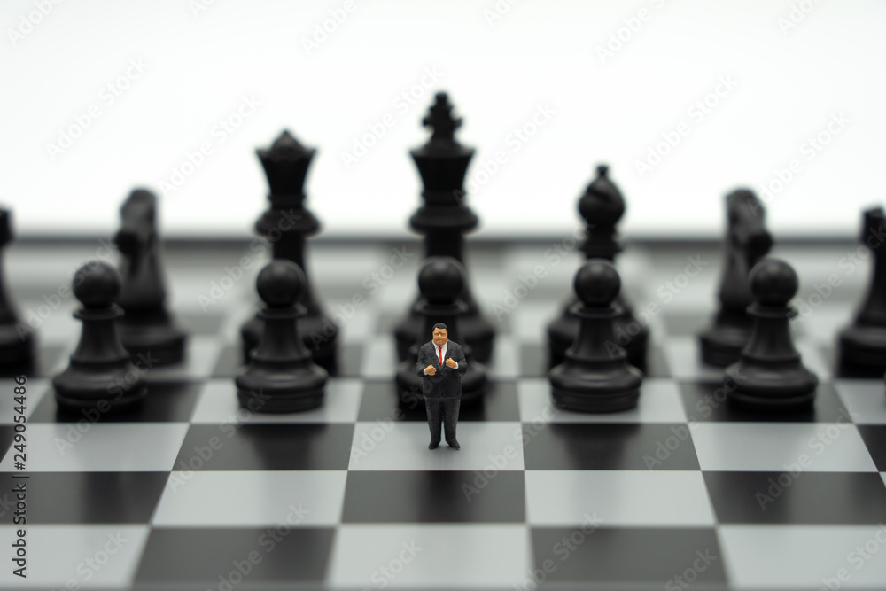 Miniature people businessmen standing on a chessboard with a chess piece on the back Negotiating in business. as background business concept and strategy concept with copy space. Miniature people businessmen standing on a chessboard with a chess piece on the back Negotiating in business. as background business concept and strategy concept with copy space.