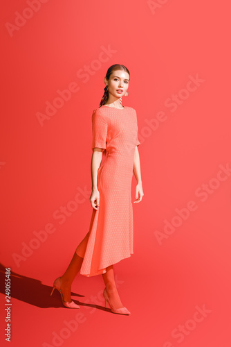 elegant stylish girl posing in living coral dress on red background