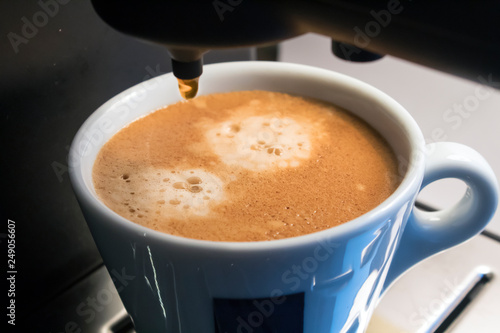 espresso coffee poured into a mug in the coffee machine