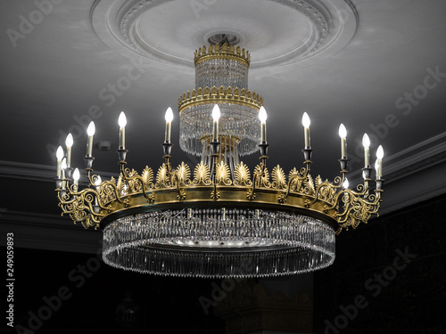 Old vintage chandelier with light candles in a palace ceiling, living room.
