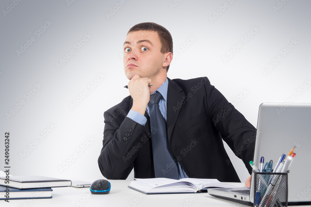 Surprised businessman with laptop computer and documents at office on gray background Surprised businessman with laptop computer and documents at office on gray background