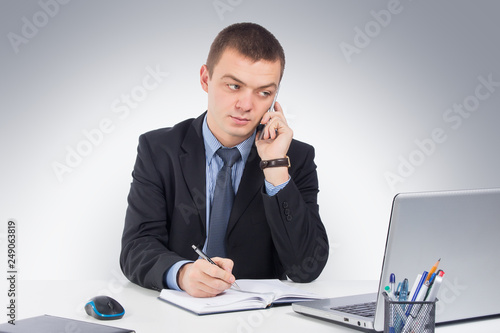 Businessman on the phone at workplace on gray background