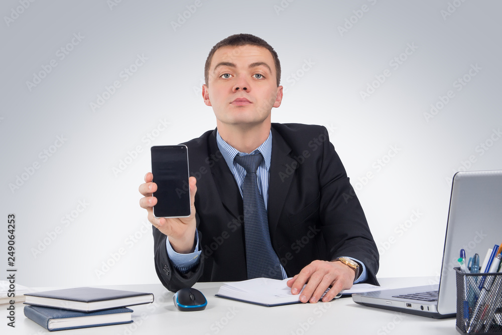 Businessman with phone at workplace on gray background Businessman with phone at workplace on gray background