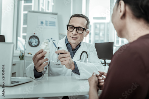 Entertained doctor using heart model as example of person heart