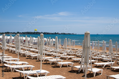 A lot of white plastic empty sunbeds and umbrellas.Empty beach © Bashigo