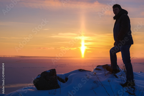 the silhouette of a man on the background of a winter landscape at sunset
