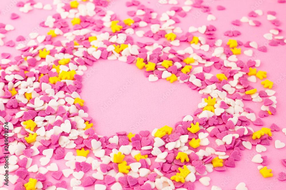 Confectionery decorations around a pink heart, sugar sprinkle sweets background for wallpaper, card, invitation or poster. Valentines day or abstract love concept