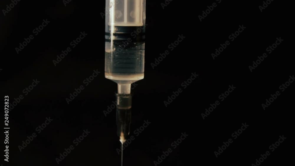 Medical syringe with liquid on black background. Close up. research scientist hand Medical syringe with liquid on black background. Close up. research scientist hand
