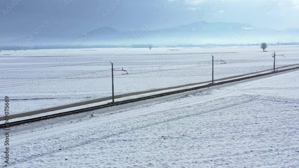 Aerial view with drone flying low over the railway winter landscape fields covered with cold white snow Aerial view with drone flying low over the railway winter landscape fields covered with cold white snow