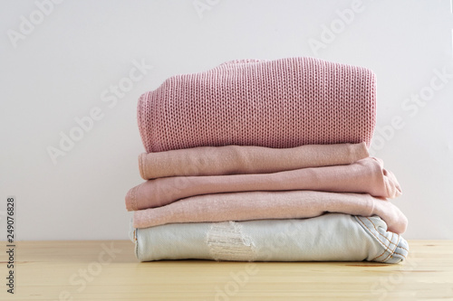 Stack of clothes. Jeans, shirt, dress, sweater on wooden table and white background isolation.