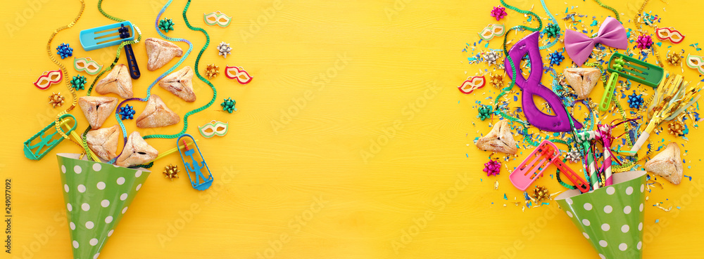 Purim celebration concept (jewish carnival holiday) over wooden yellow background. Banner.