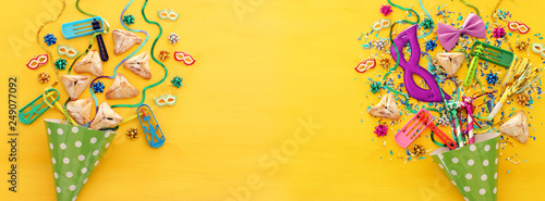 Purim celebration concept (jewish carnival holiday) over wooden yellow background. Banner.