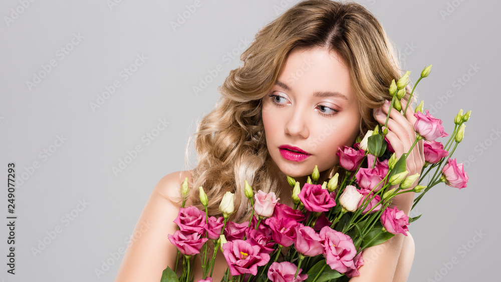 naked attractive blonde woman posing with spring Eustoma flowers bouquet isolated on grey