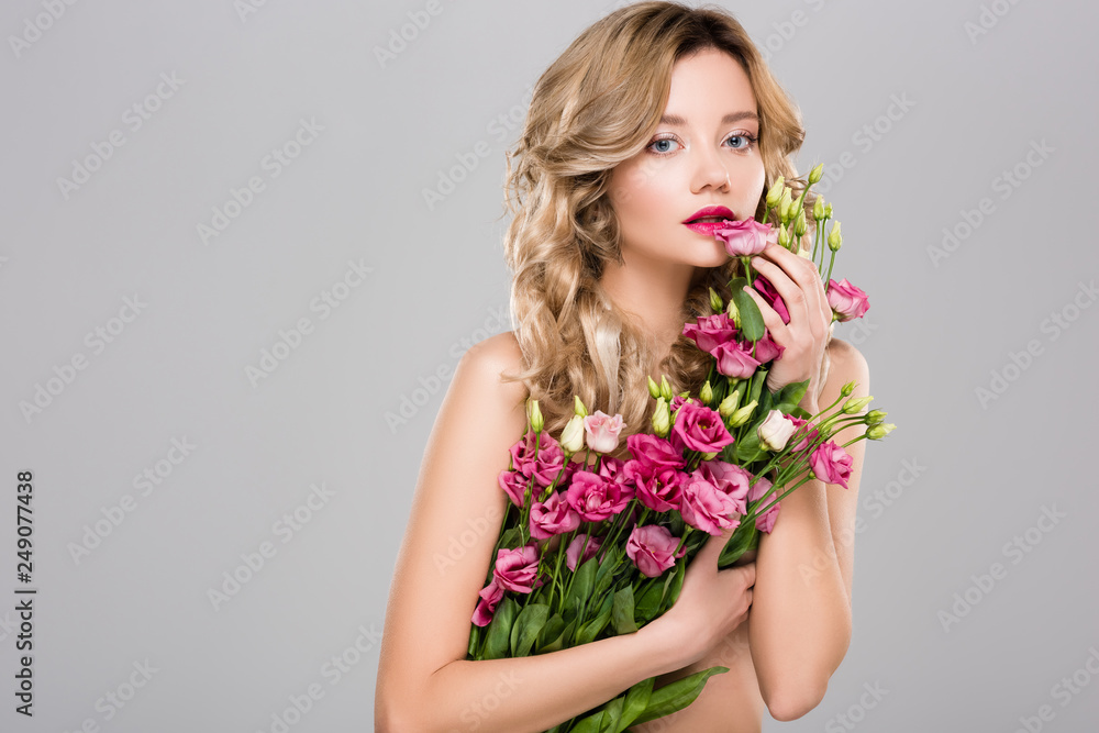 nude beautiful woman posing with spring Eustoma flowers bouquet isolated on grey