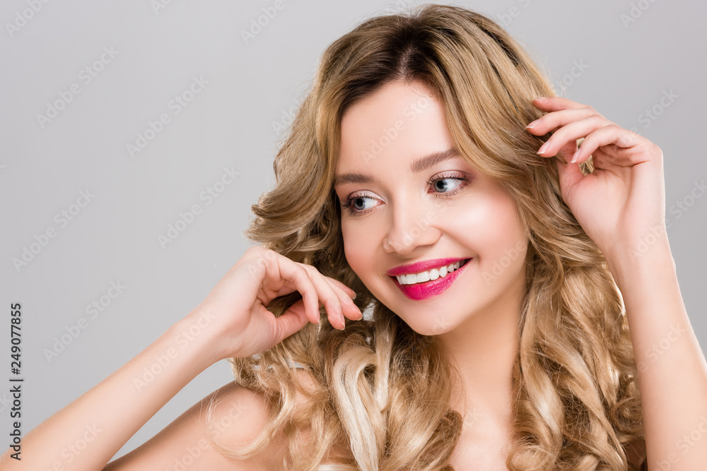Naklejka premium przetargu nago uśmiechnięta młoda kobieta dotyka włosów na szarym tle