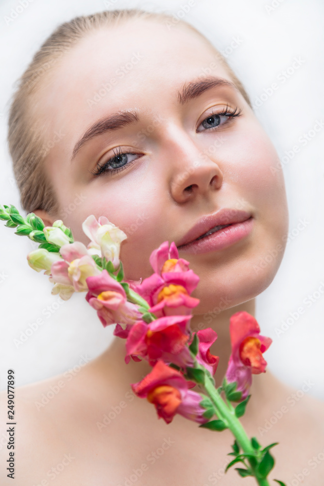 Beautiful girl's face with color flower near
