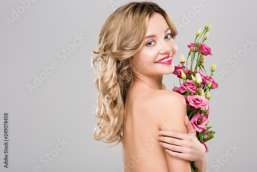 naked beautiful cheerful spring young woman holding bouquet of Eustoma flowers isolated on grey