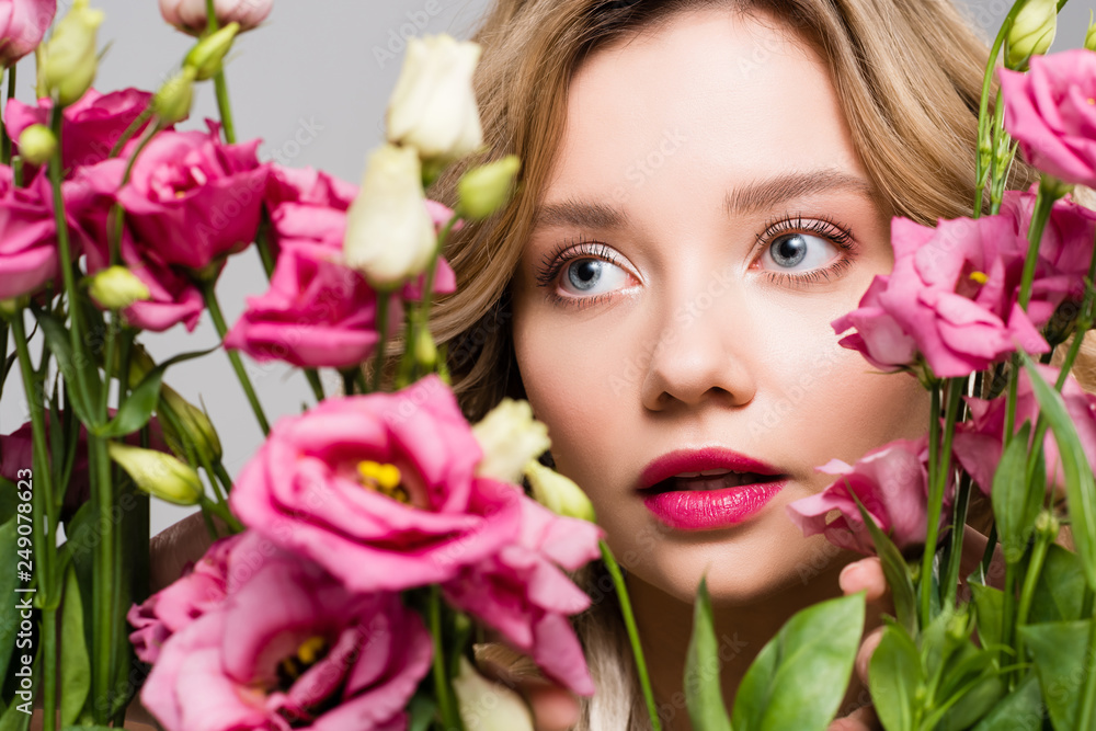 close up of beautiful spring young woman hiding behind bouquet of Eustoma flowers isolated on grey close up of beautiful spring young woman hiding behind bouquet of Eustoma flowers isolated on grey