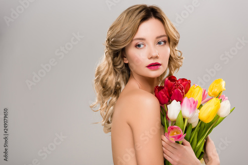 young naked spring woman holding bouquet of colorful tulips isolated on grey