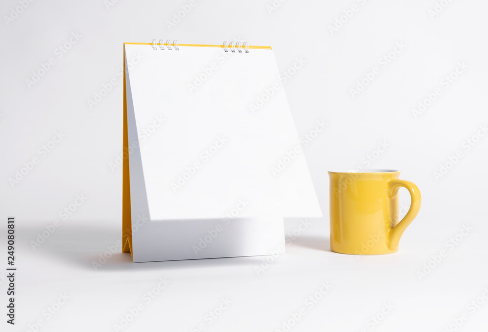 Blank paper spiral calendar and yellow cup for mockup template advertising and branding background. Blank paper spiral calendar and yellow cup for mockup template advertising and branding background.