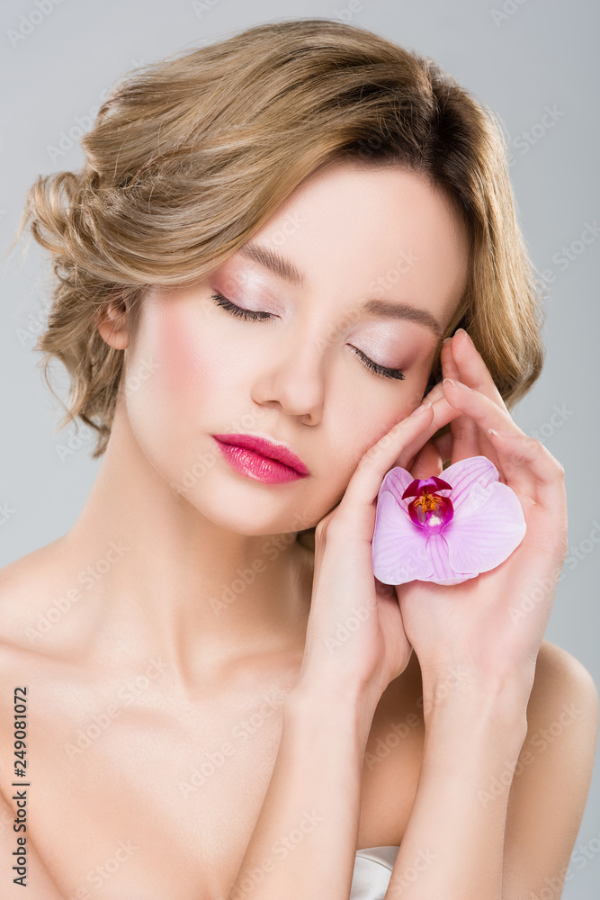 portrait of young tender woman with closed eyes holding purple orchid isolated on grey portrait of young tender woman with closed eyes holding purple orchid isolated on grey