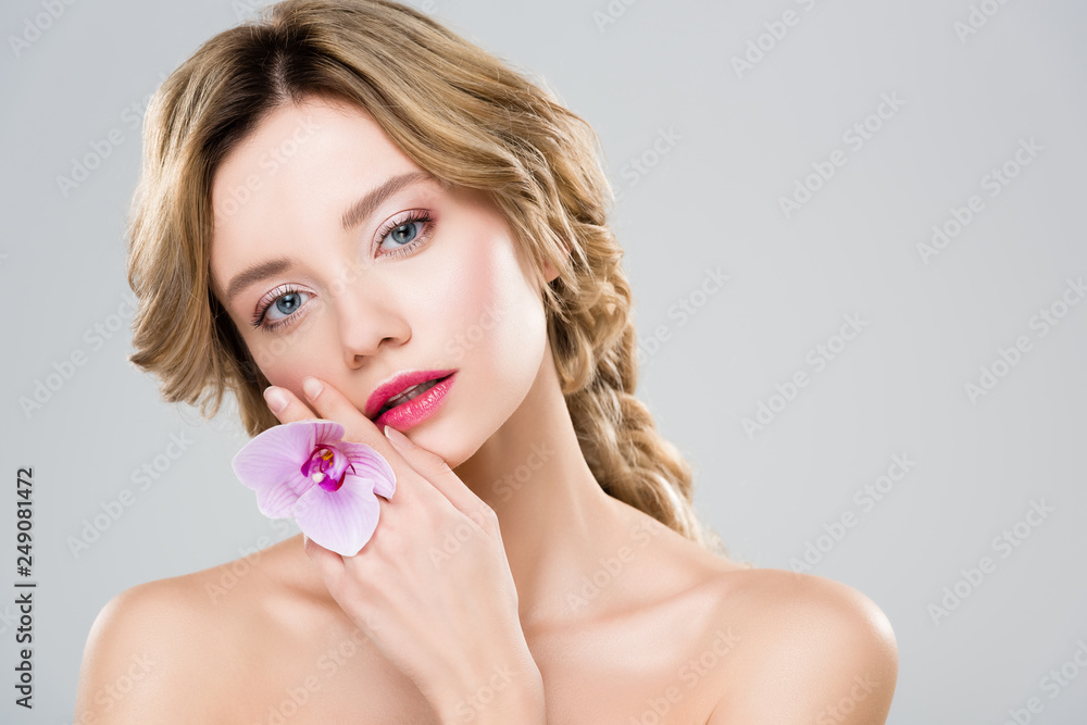attractive girl holding flower near face isolated on grey attractive girl holding flower near face isolated on grey