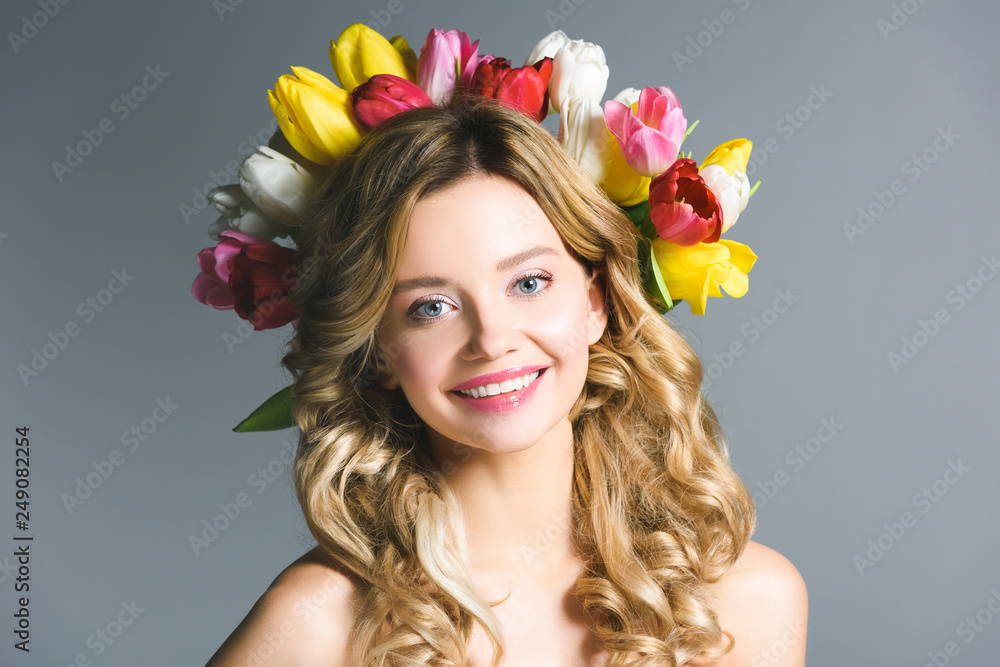 Naklejka premium happy girl with wreath of flowers on hair isolated on grey