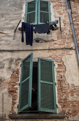 clothes hanged by green window blind of a building photo