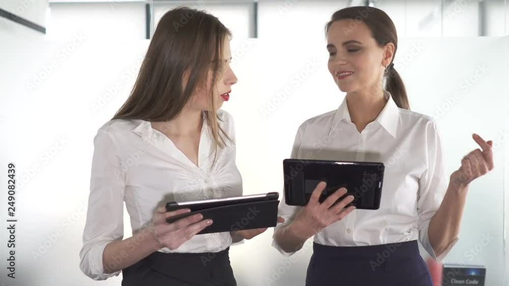 4К. Two pretty business woman in office working by tablet and discuss. 4К. Two pretty business woman in office working by tablet and discuss.