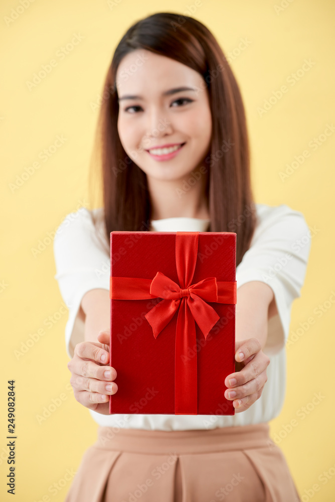 Portrait of a happy pretty asian woman holding present box while standing Portrait of a happy pretty asian woman holding present box while standing