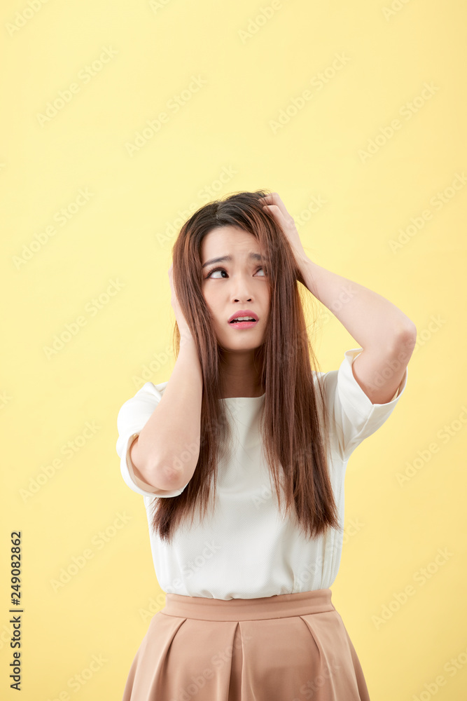 Young Asian woman having a stress isolated on yellow background. Young Asian woman having a stress isolated on yellow background.