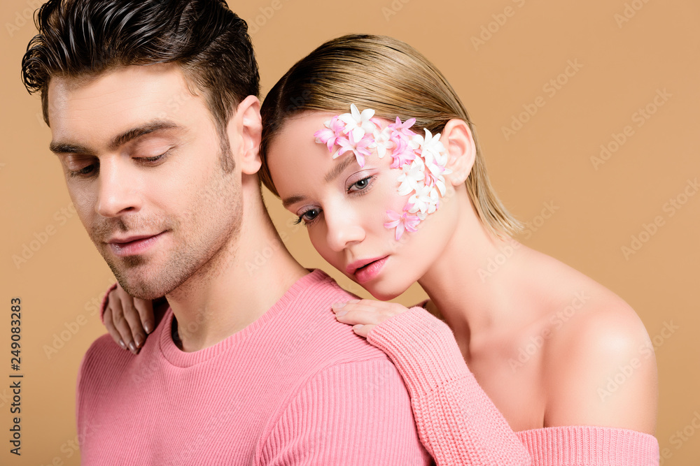 attractive woman with flowers on face hugging man isolated on beige attractive woman with flowers on face hugging man isolated on beige