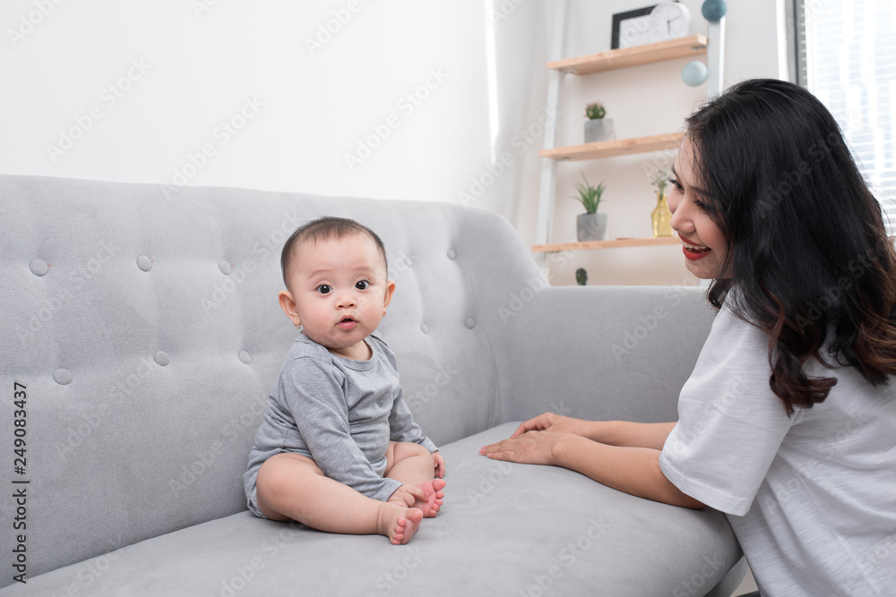 Young mother with her one years old little son dressed in pajamas are relaxing and playing in the living room at the weekend together, lazy morning, warm and cozy scene. Selective focus. Young mother with her one years old little son dressed in pajamas are relaxing and playing in the living room at the weekend together, lazy morning, warm and cozy scene. Selective focus.