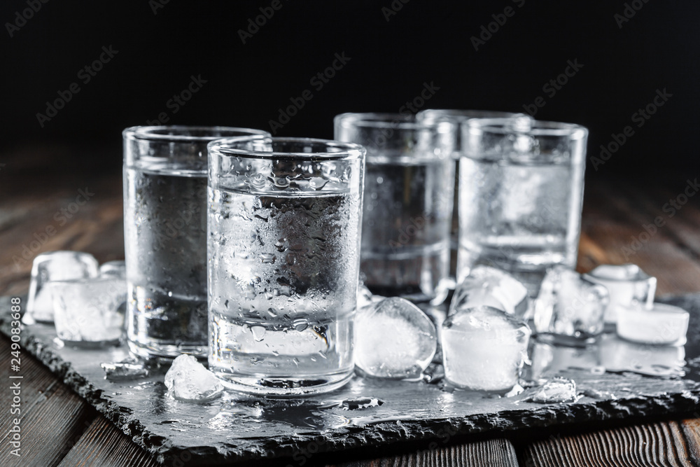 Vodka in shot glasses on rustic wood background